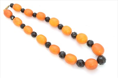 Lot 184 - A butterscotch amber and jet necklace.
