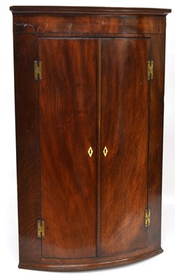 Lot 323 - George III mahogany bow-front wall hanging corner cupboard