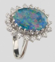 Lot 357 - Oval opal doublet within a band of diamonds, set