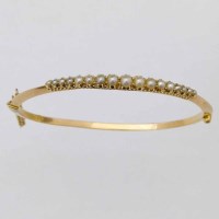 Lot 291 - Gold and pearl hinged bangle, the half hoop set