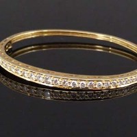 Lot 283 - 18ct gold hinged bangle set with diamonds.