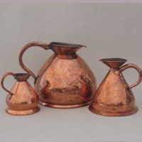 Lot 440 - Three graduated copper jugs.
