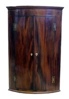 Lot 413 - George III mahogany two door bow-front corner cupboard.